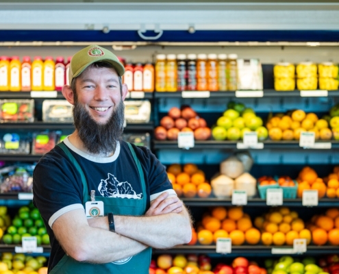 Friendly City Food Co-op employee posing in front of produce aisle