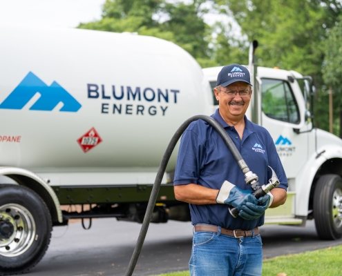 Blumont Energy employee standing in front of propane delivery truck, preparing for a propane delivery. Custom photography by Estland.