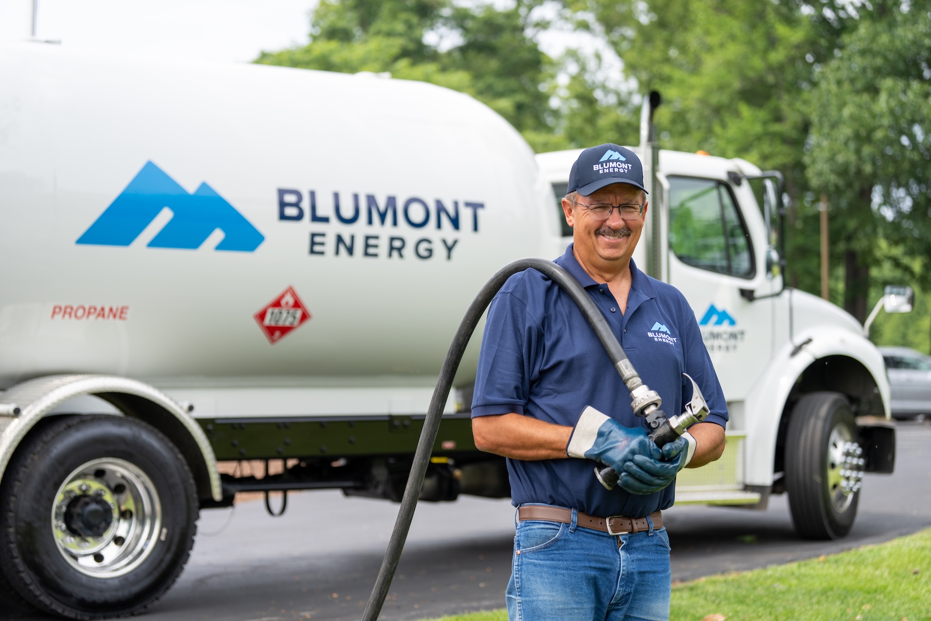 Blumont Energy employee standing in front of propane delivery truck, preparing for a propane delivery. Custom photography by Estland.