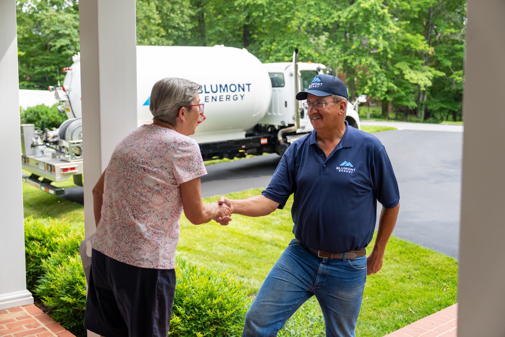 Blumont Energy delivery person shaking hands with customer outside the customers home during a propane delivery. Custom photography by Estland.