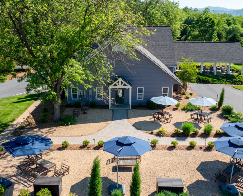 A building with a landscaped outdoor space with blue umbrellas and seating areas.