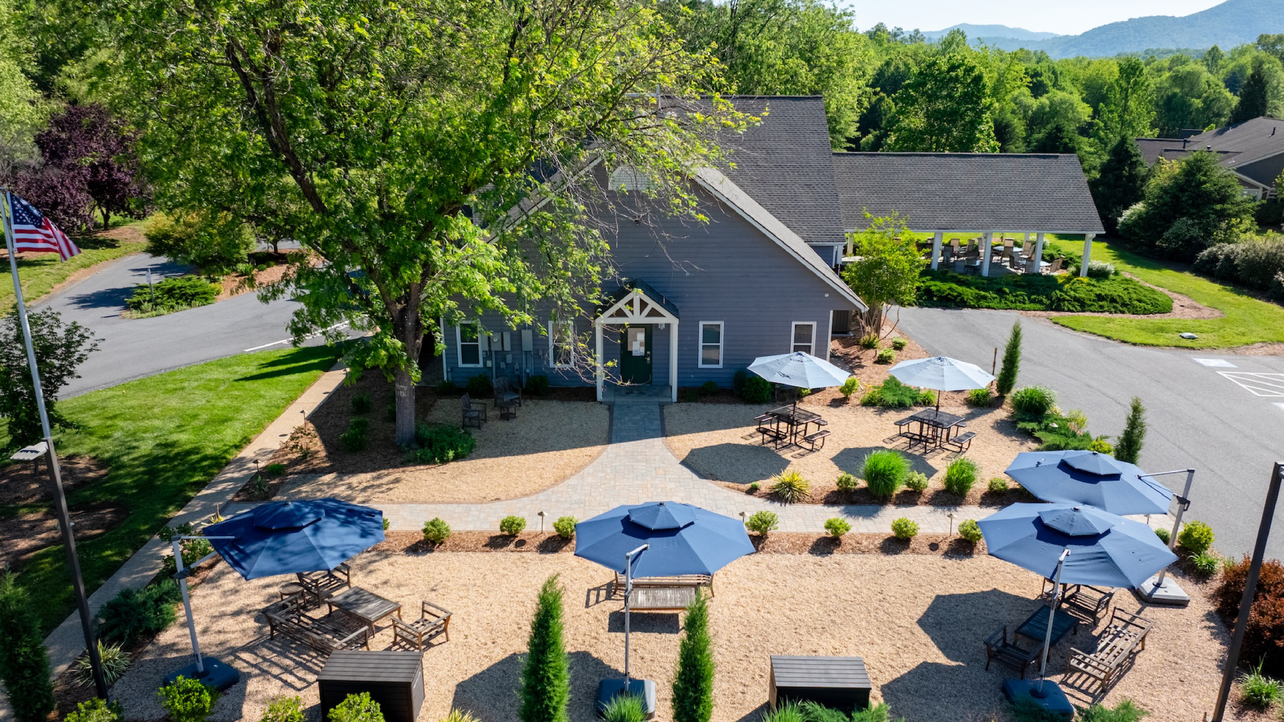A building with a landscaped outdoor space with blue umbrellas and seating areas.